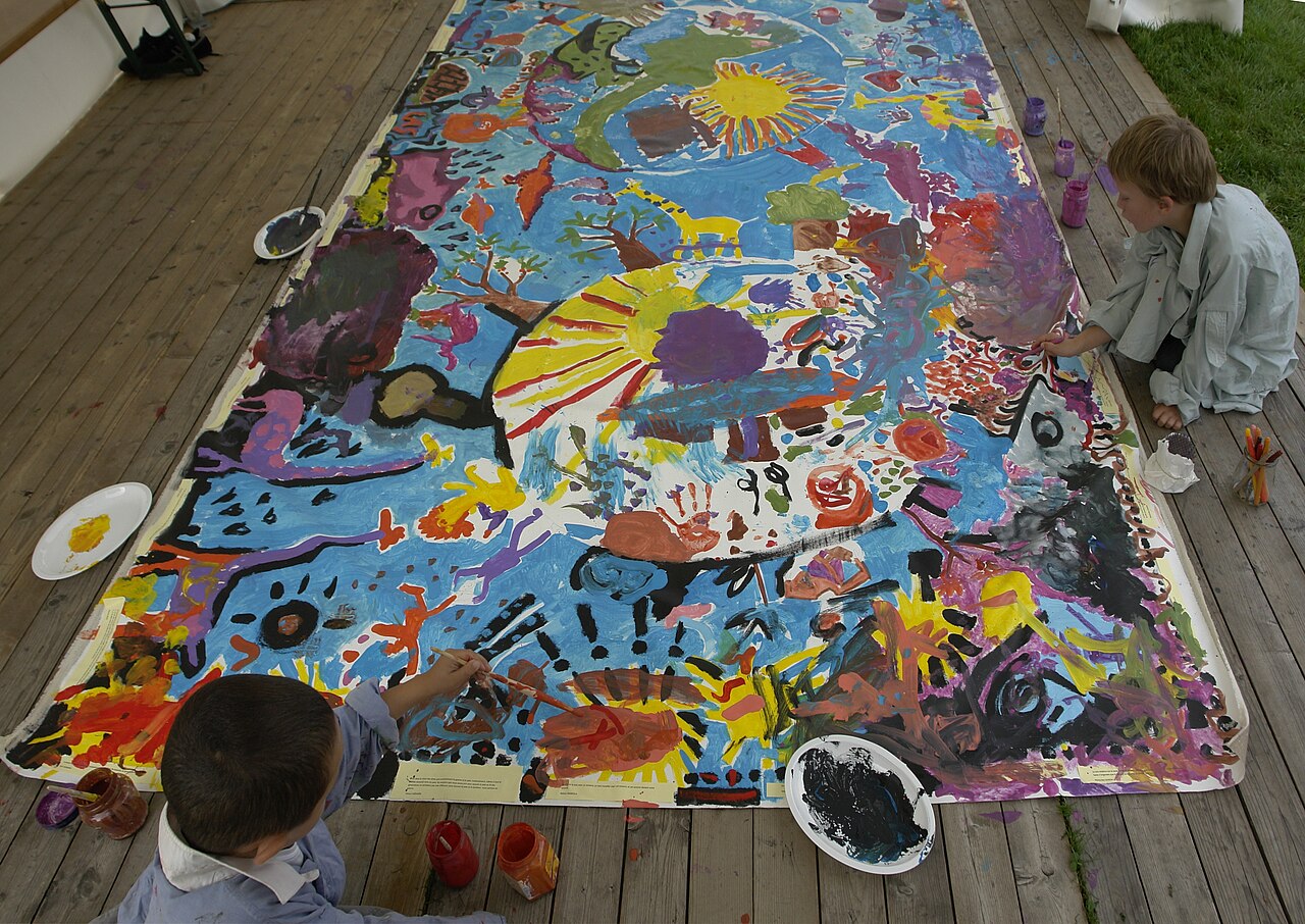 Children painting a large floor canvas