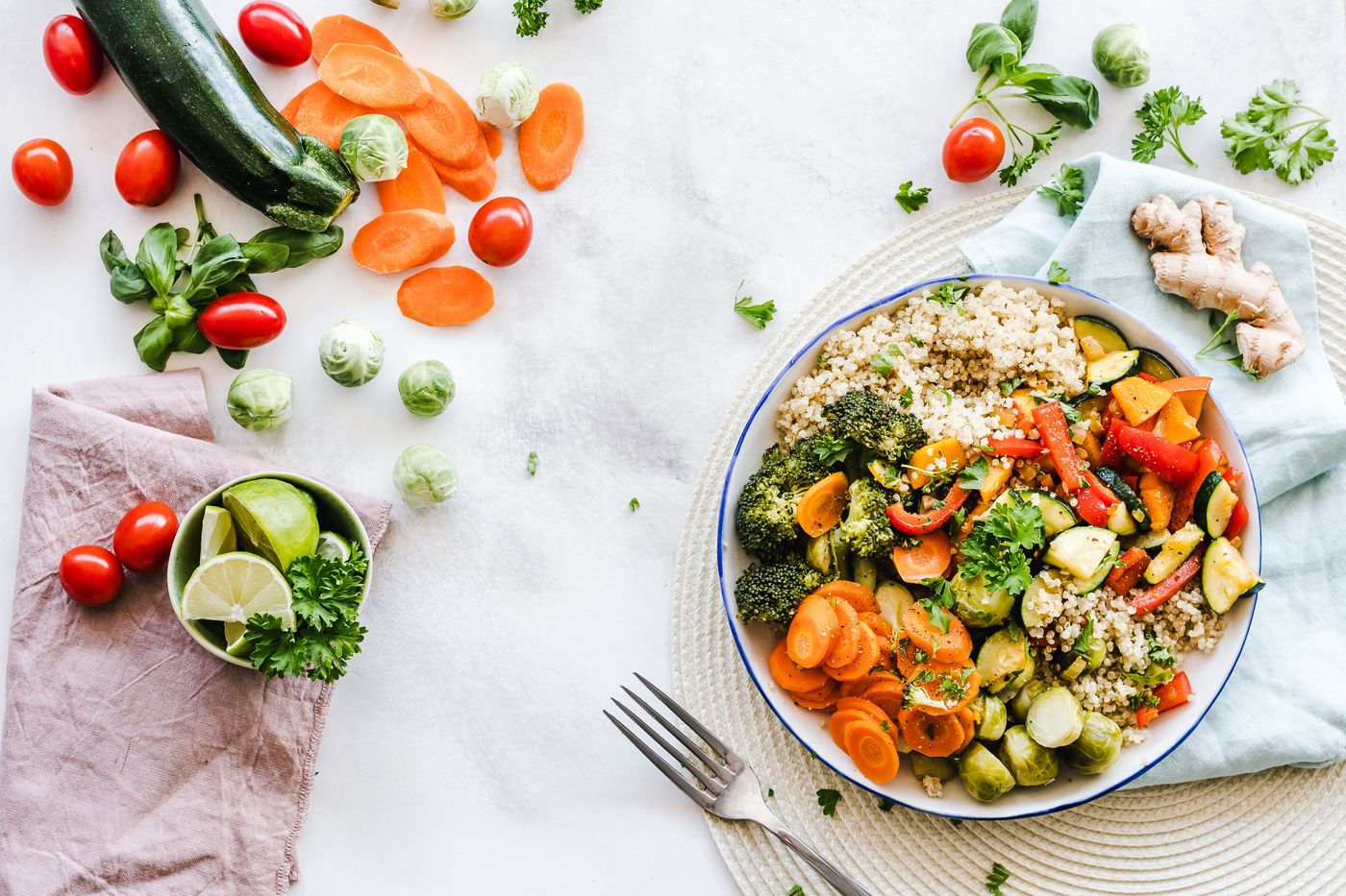 Bowl of grains and roasted vegetables with raw produce nearby
