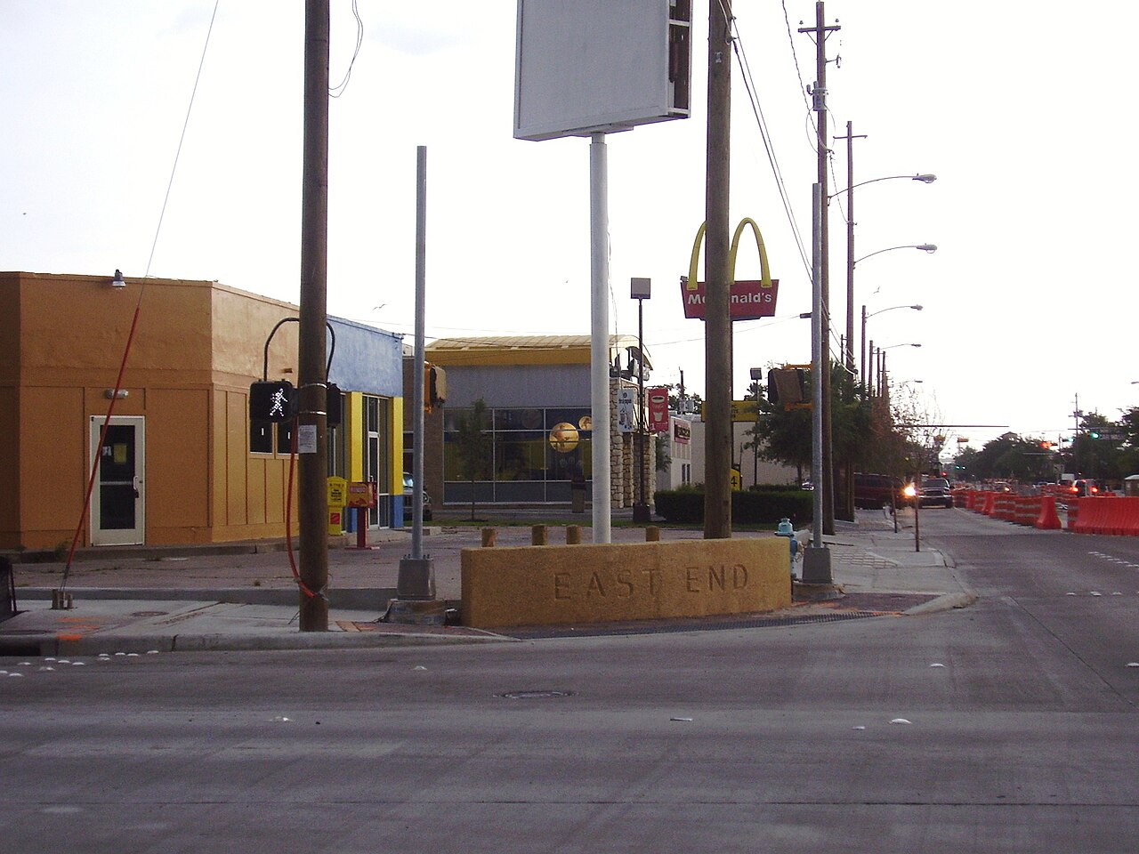 Concrete East End marker at a Houston street corner with shops and a McDonald’s sign in the distance