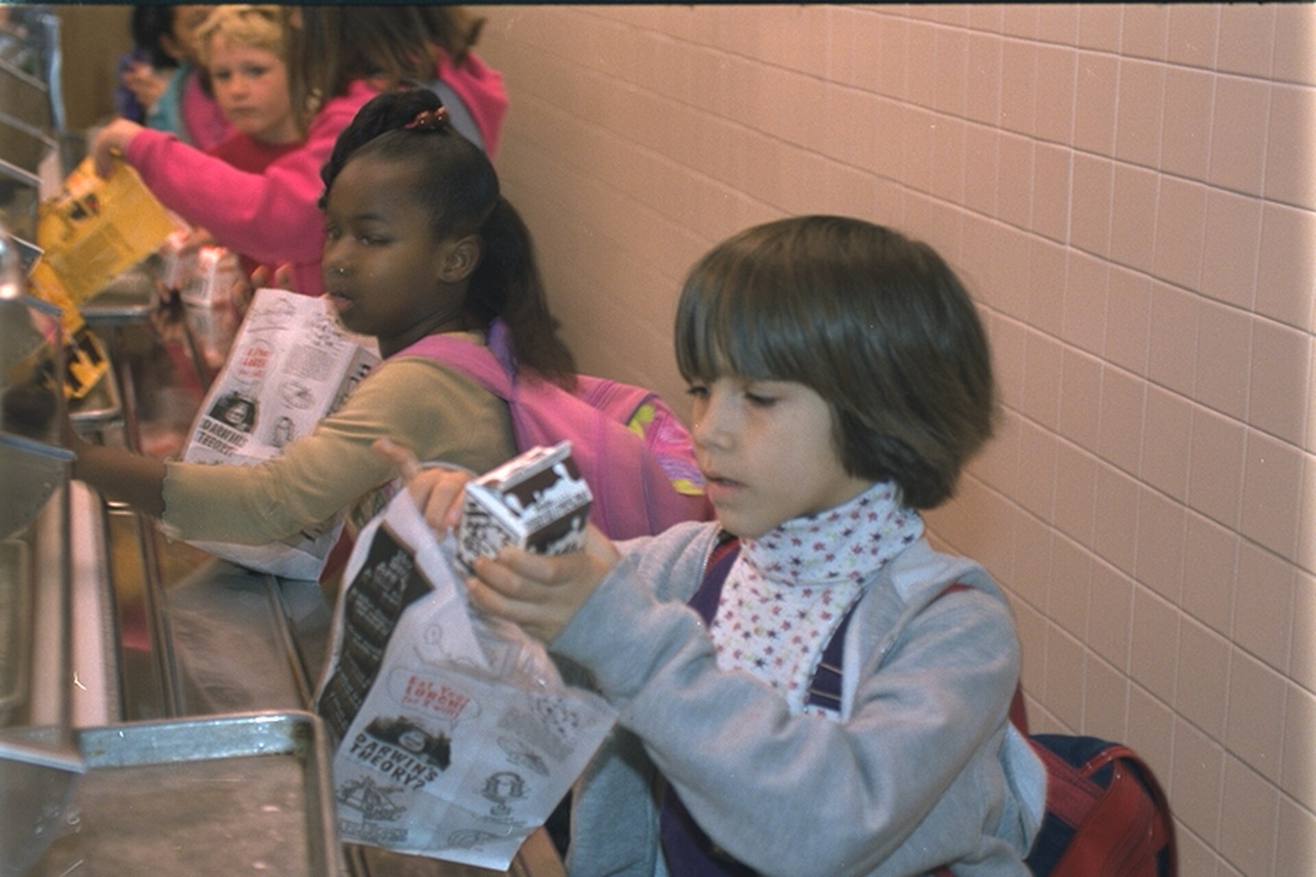Children in a cafeteria line with milk cartons