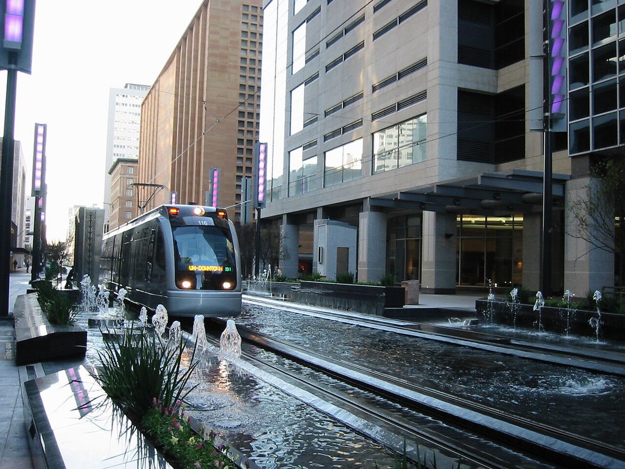 Houston METRORail train marked UH-Downtown at a downtown fountain plaza