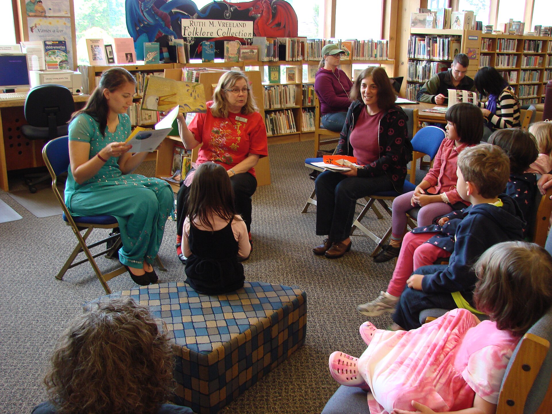 Adults and children sitting in a library circle during storytime